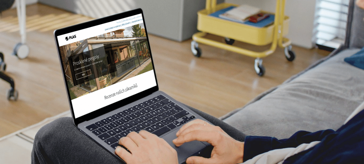 plas-mockup - aitomdigital.com Plas na obrazovce nootebook. Ten notebook má někdo na klíně a sedí na gauči