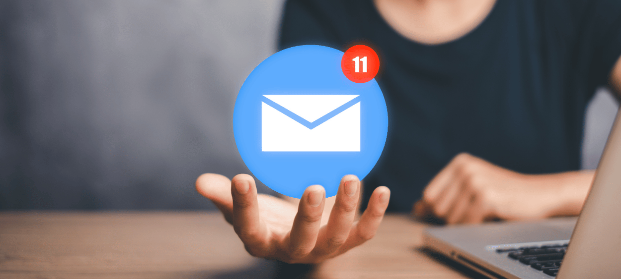 logo-email-v-ruce - aitomdigital.com Levitující ikona v rukou osoby sedící u stolu. Osoba má před sebou notebook