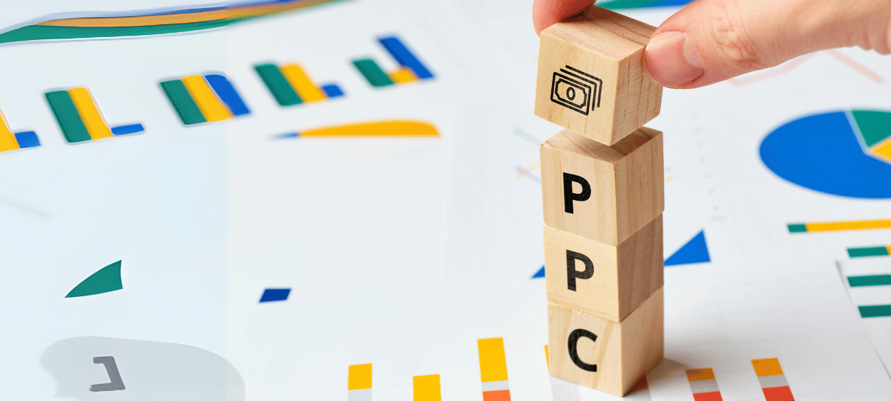 ppc-kampan-kosticky - aitomdigital.com Na obrázku jsou kostičky na každé kkostičce je jedno písmeno, dohromady trvoří slovo ppc. V pozadí jsou papíry s diagramy